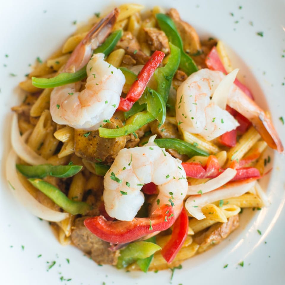 Penne pasta with shrimp, chicken, red and green bell peppers, and onions in a creamy sauce.
