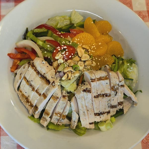 Grilled chicken salad with mandarin oranges, bell peppers, onions, and sesame seeds.
